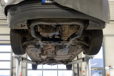 Bir araba kaldırma platformunda bir araba tamirhanesine gidiyor. 