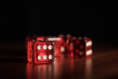 Tahta bir tabakta yan yana beş kırmızı zar var.