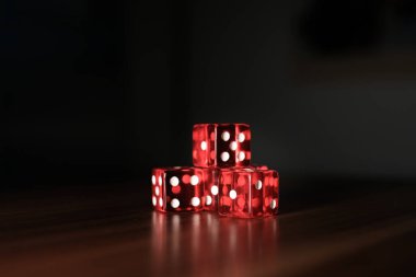 Tahta bir tabakta yan yana beş kırmızı zar var.