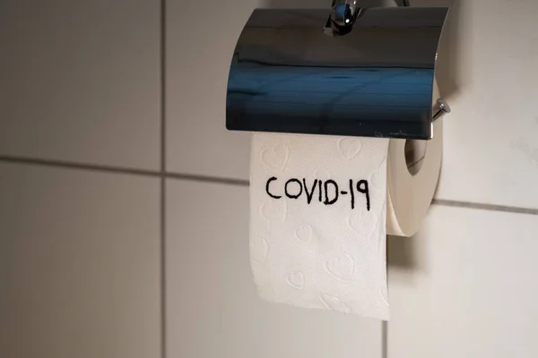 on a white toilet paper roll stands Covid-19