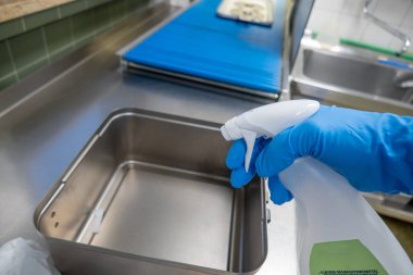 Metal bir kap sprey şişesinden dezenfektan ile dezenfekte edilir.