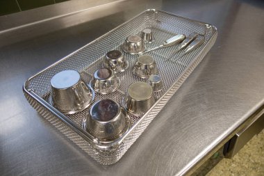 çeşitli cerrahi aletler bir iş yüzeyinde elek içinde yatar.