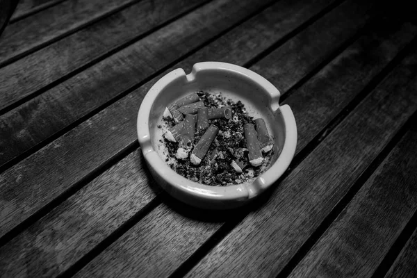 Rabos Cigarro Estão Esmagados Cinzeiro Branco Sobre Uma Mesa Madeira — Fotografia de Stock