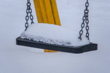 Bir çocuk salıncağının koltuğunda oldukça fazla kar var.