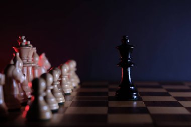 Siyah kral, satranç tahtasındaki beyaz taşların önünde tek başına.
