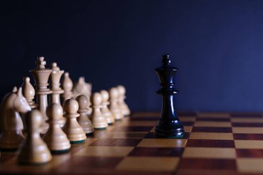 Siyah kral, satranç tahtasındaki beyaz taşların önünde tek başına.