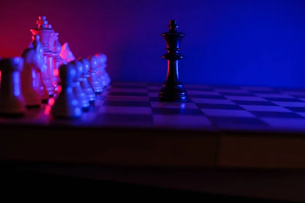 黒の王はチェス盤の白い駒の前に一人でいて — ストック写真