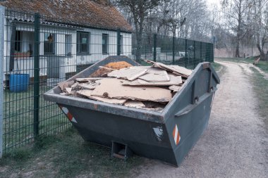 Gri bir çöp konteynırında bir sürü tahta tahta var.