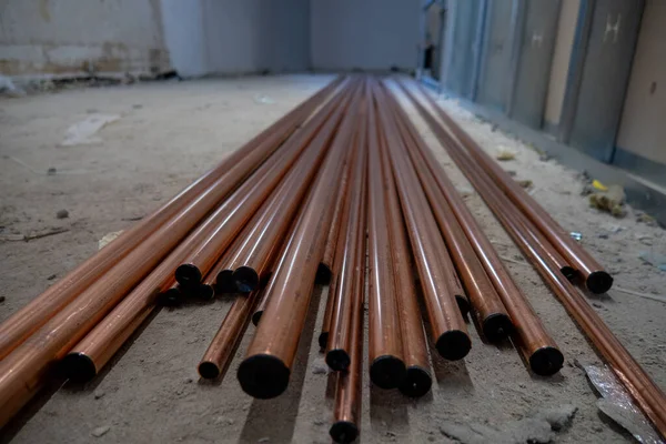 on the floor of a construction site are many copper pipes