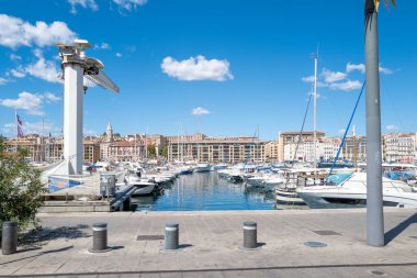 Fransa 'nın Marsilya kentindeki Eski Liman' da güneşli güzel bir gün, açık mavi gökyüzünün altında limana yanaşmış yat ve yelkenlileri gösteriyor. Rıhtım tarihi binalar ve Akdeniz mimarisi ile çevrili.