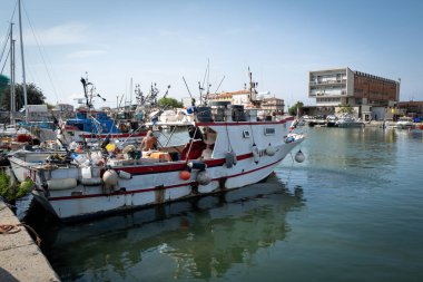Geleneksel balıkçı tekneleri güneşli bir günde küçük bir limana yanaştılar. Rıhtımdaki renkli tekneler, balıkçı ağları, ipler ve ekipmanlar, çalışan bir limanın otantik atmosferini yansıtıyor. Sakin su, mavi gökyüzü ve deniz ayrıntıları.