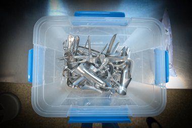 Şeffaf plastik bir kapta sterilize edilmiş jinekolojik spekulum ve tıbbi muayene aletleri koleksiyonu. Paslanmaz çelik aletler, profesyonel sağlık standartları, hijyen ve