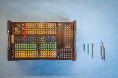 Yüksek çözünürlüklü ortopedik implant tepsisi ve steril mavi cerrahi kumaş üzerinde renk kodlu vidalar. Tepsinin yanında farklı boyutlarda ve malzemelerde çeşitli ortopedik vidalar var.