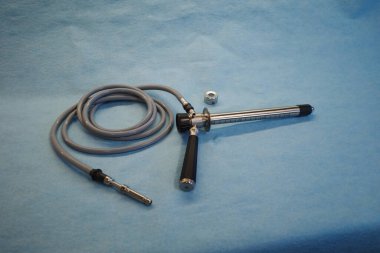 Temiz mavi cerrahi arka plan üzerine yerleştirilmiş esnek hortum ve metal sondayla tıbbi endoskopik bir aletin yüksek kaliteli stüdyo fotoğrafı. Görüntü klinik muayenelerde, gastroenterolojide kullanılan profesyonel bir teşhis cihazını gösteriyor.,