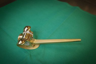 Steril yeşil cerrahi kumaşa yerleştirilmiş titanyum diz protezinin yakından görüntüsü. Ortopedik implant yüksek kaliteli titanyumdan yapılmış. Bu da onu hafif, dayanıklı, aşınmaya dayanıklı ve hipoalerjenik yapıyor. Hastalarım için ideal.