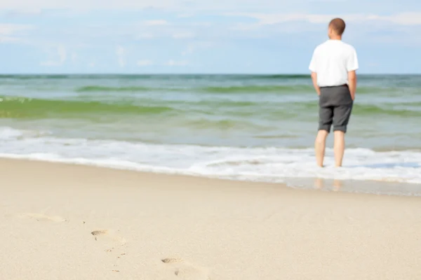 Beach ember állt a víz vissza Nézd sekély dof lábnyomok homok — Stock Fotó