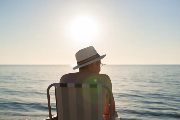 Man zit zonsondergang strand achtergrondverlichting lens flare selectieve aandacht — Stockfoto