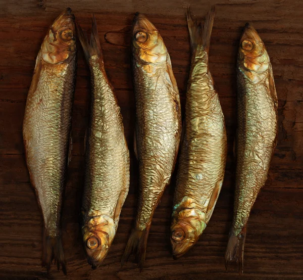 Herring sprat fish smoked on wooden table background — Stock Image Herring sprat fish smoked on wooden table background Stock Photo