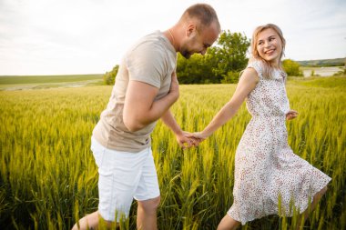 Adam ve kız yeşil çimlerin üzerinde koşuyorlar ve gülümsüyorlar..