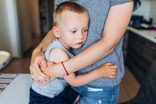 A mãe abraça o filho na cozinha. Família na cozinha. — Fotografia de Stock