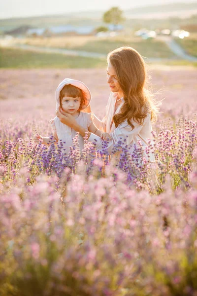 Matka objímá dceru při západu slunce na levandulovém poli. — Stock fotografie