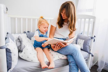 Genç anne yatmadan önce kızına bir kitap okur..