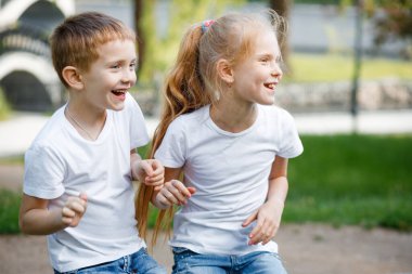 Neşeli çocuklar parkta yeşil bankta oynuyorlar..