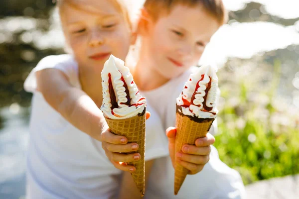 Children eat ice cream in the park.