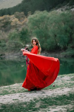 Bir buket nar ve gülle kırmızı elbiseli genç gelin..