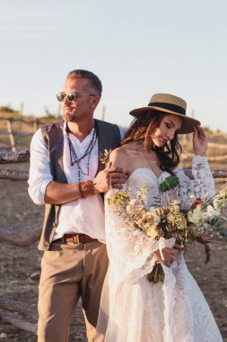Çiftlikte boho tarzında bir düğün çifti. Tasarımcı düğün buketi.