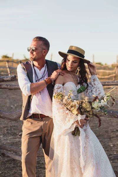 Wedding couple in the boho style on the ranch. Designer wedding bouquet.