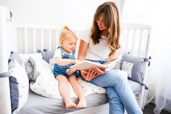 A fiatal anya könyvet olvas a lányának lefekvés előtt.. — Stock Fotó