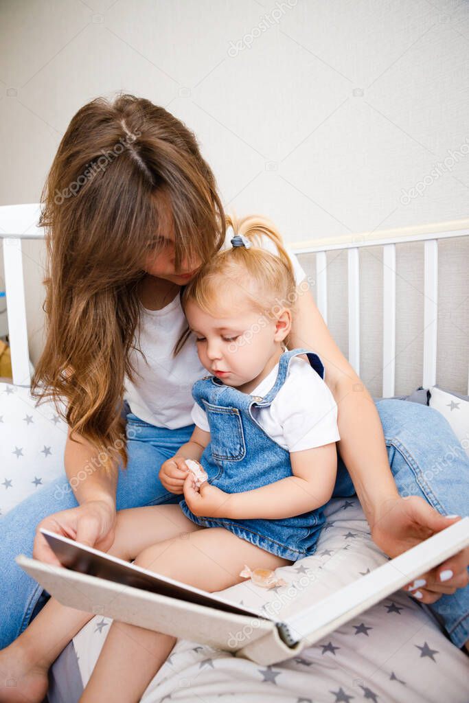 Young mother reads a book to her daughter before bedtime.