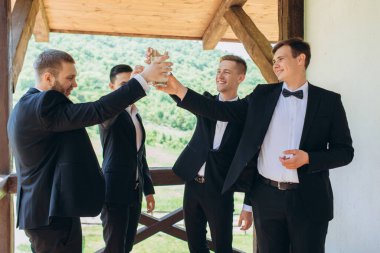 Damat ve arkadaşları düğünü kutluyorlar. Takım elbiseli adamlar. Erkeklerin duyguları ve dostluğu.