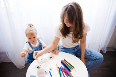 Anne ve kızı birlikte resim yapıyorlar. Çocuk annesiyle resim çiziyor..