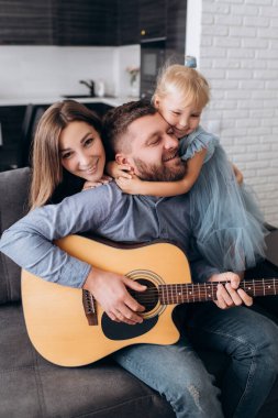 Aile gitar çalar. Baba karısı ve kızı için gitar çalar..