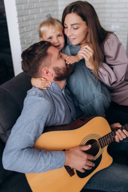 Aile gitar çalar. Baba karısı ve kızı için gitar çalar..