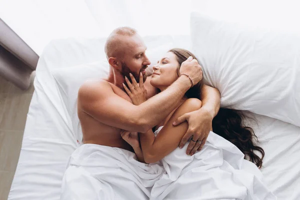 Casal amoroso na cama em lençóis brancos. Fique em casa. — Fotografia de Stock