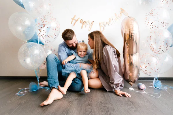 Rodina slaví narozeniny své malé dcery. Narozeninová oslava v modrých šatech a balónech. — Stock fotografie