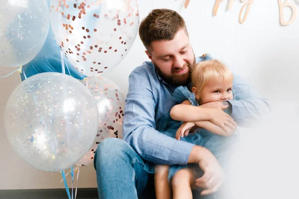 Ojciec i córka świętują urodziny swojej córeczki. Uroczystości urodzinowe w niebieskich sukienkach i balonach. — Zdjęcie stockowe