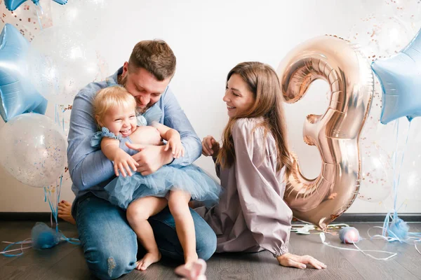 Familjen firar sin lilla dotters födelsedag. Födelsedag firande i blå klänningar och ballonger. — Stockfoto