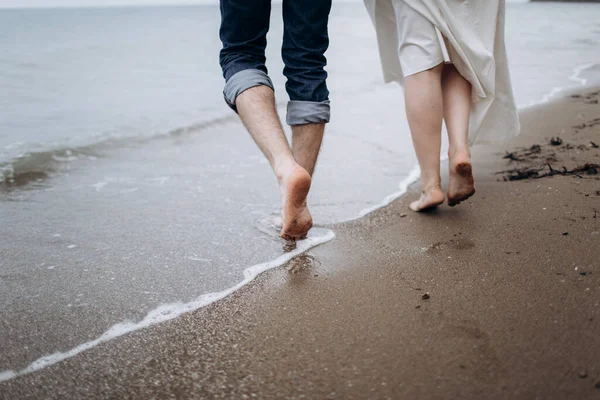 Dois pares de pernas de amantes caminham na areia na praia. — Fotografia de Stock