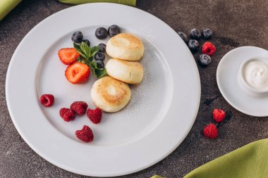 Nutritious vegetarian breakfast with cheesecakes and berries. 