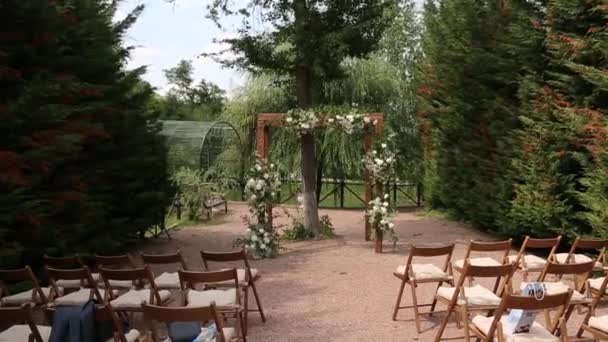 Rusztikus esküvői ív egy kilépési ceremóniához fehér és virágokkal díszítve. — Stock videók