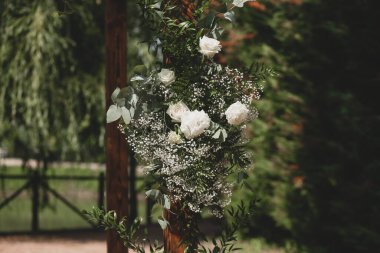 Parkta beyaz çiçeklerle boho tarzında düğün kemeri.