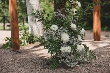 Parkta beyaz çiçeklerle boho tarzında düğün kemeri.