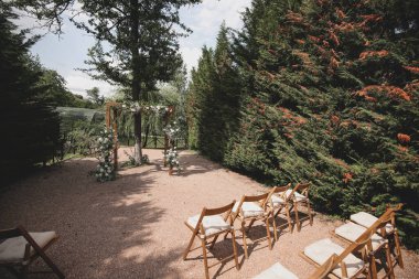 Parkta beyaz çiçeklerle boho tarzında düğün kemeri.