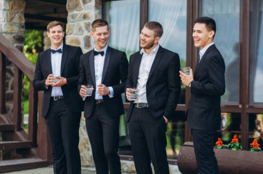 Damat ve arkadaşları düğünü kutluyorlar. Takım elbiseli adamlar. Erkeklerin duyguları ve dostluğu.