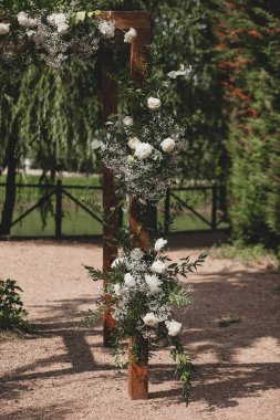 Parkta beyaz çiçeklerle boho tarzında düğün kemeri.