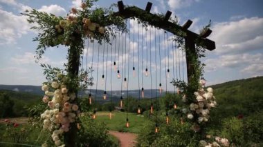 Boho stilinde düğün kemeri Parkta beyaz çiçekler ve ampuller.